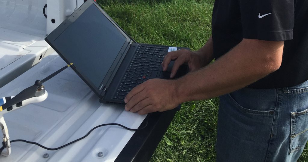 Certified agronomist consultant using laptop and drone to help with Precision Ag
