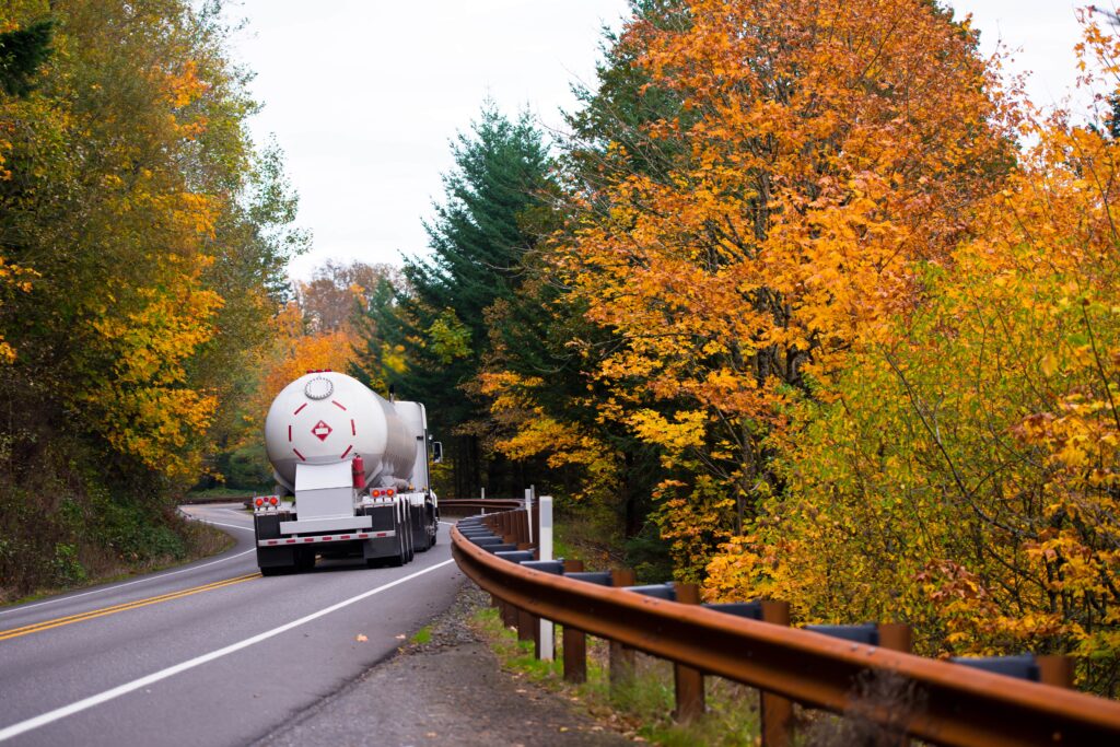 big rig truck with propane tank on winding autumn road